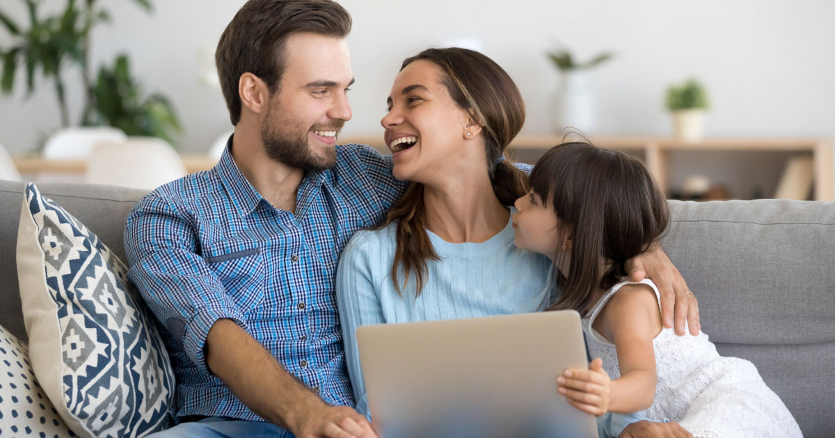 Family man sitting on couch with wife and daughter