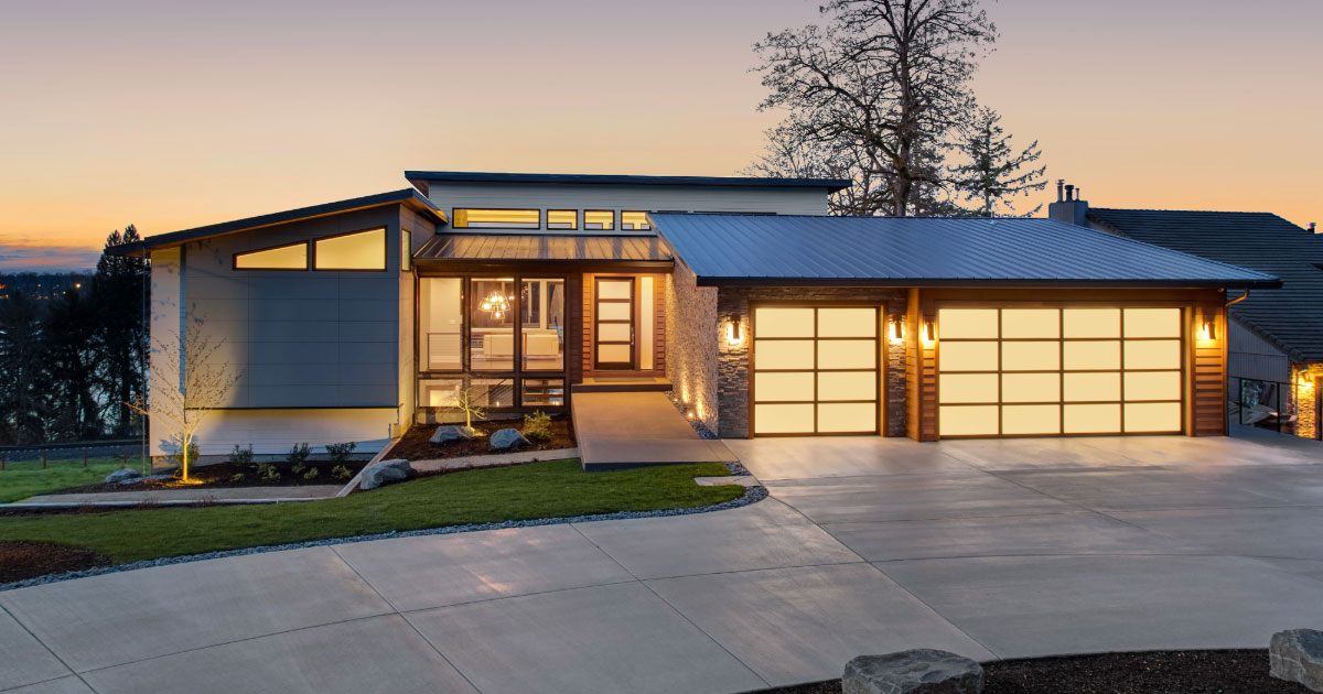 Modern newer house exterior photo with all lights on - taken at dusk.