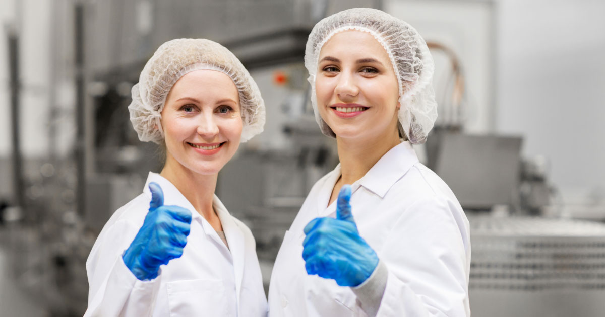 Two women lab workers giving a thumbs up to the camera