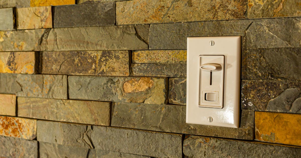 Dimmer switch installed on wall with stone facade