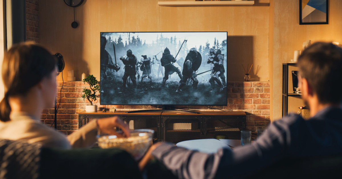 Family sitting on couch watching favorite TV show together