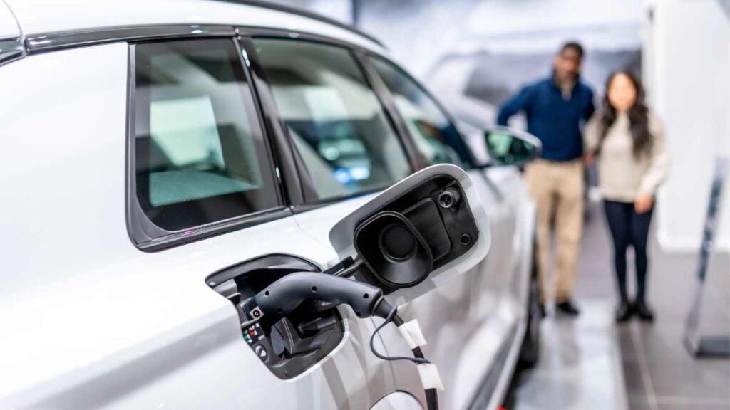 couple looks at car parked in garage with EV charger plugged in