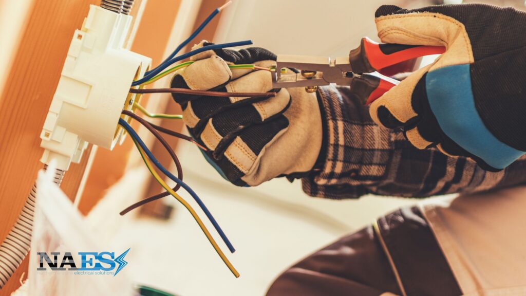 Electrician wearing yellow gloves fixes cords from a cord box